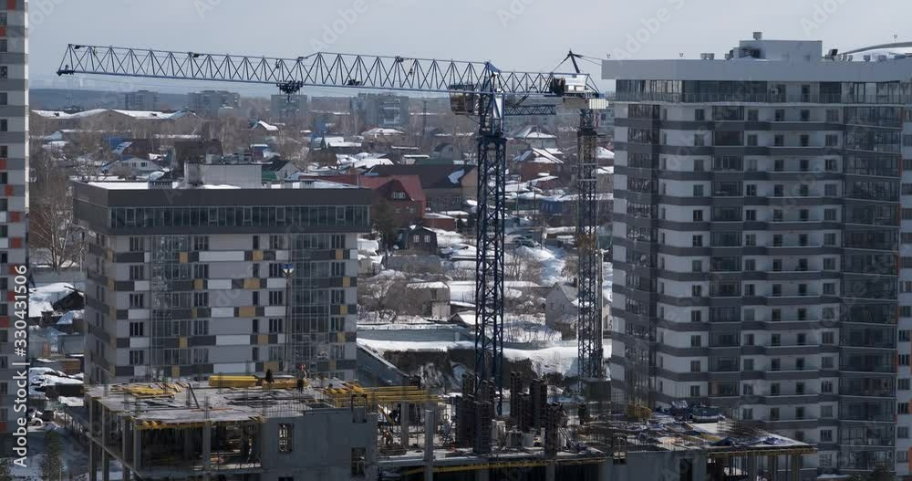 Time lapse of construction site, tower crane sways in wind, lifts load, winter construction, construction of new residential complex, general plan, sunny weather, builders working on concrete pouring Time lapse of construction site, tower crane sways in wind, lifts load, winter construction, construction of new residential complex, general plan, sunny weather, builders working on concrete pouring