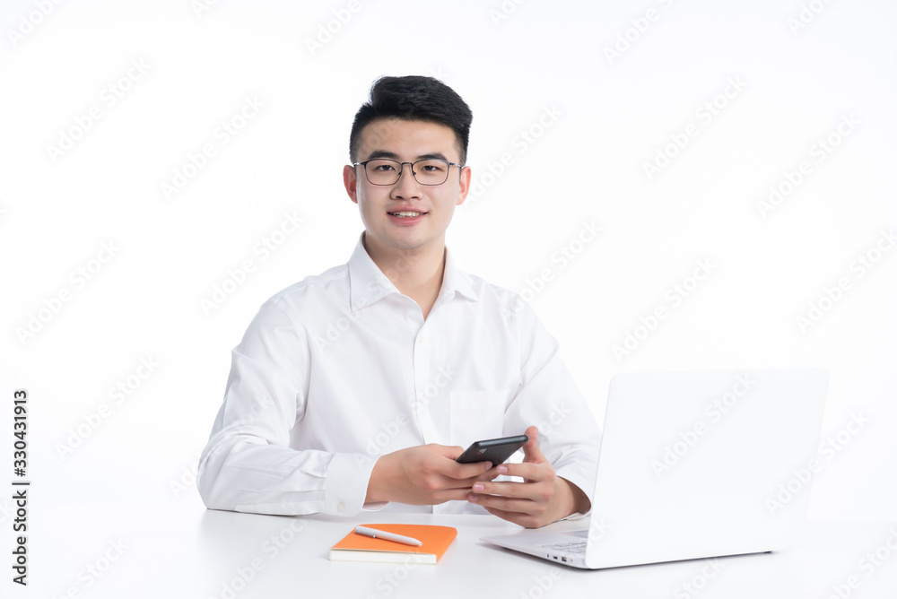 A young Asian man is using his mobile phone and laptop A young Asian man is using his mobile phone and laptop