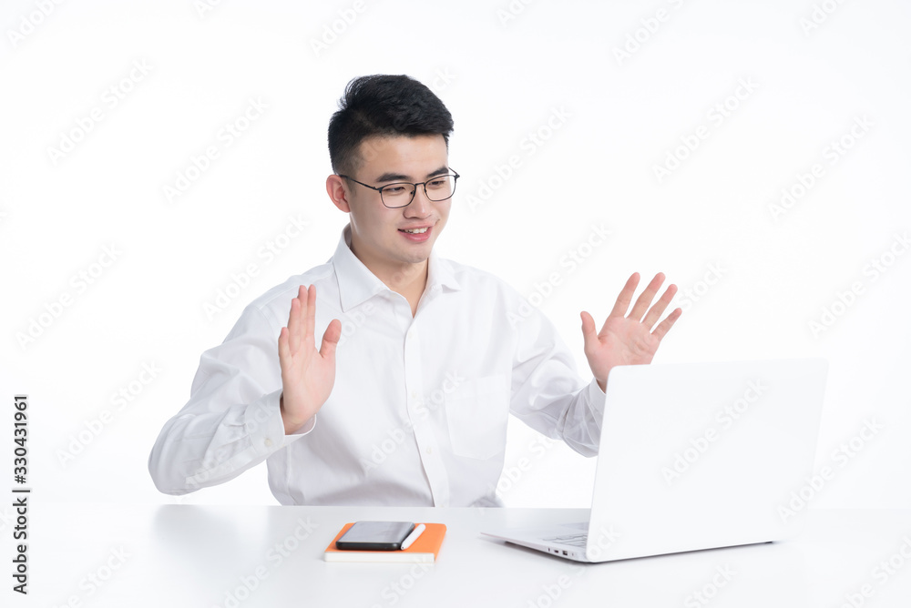 A young Asian man is using his mobile phone and laptop