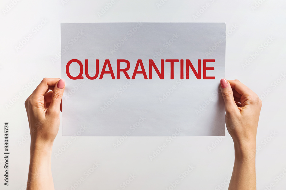 Woman's hands holding paper with text Quaranntine