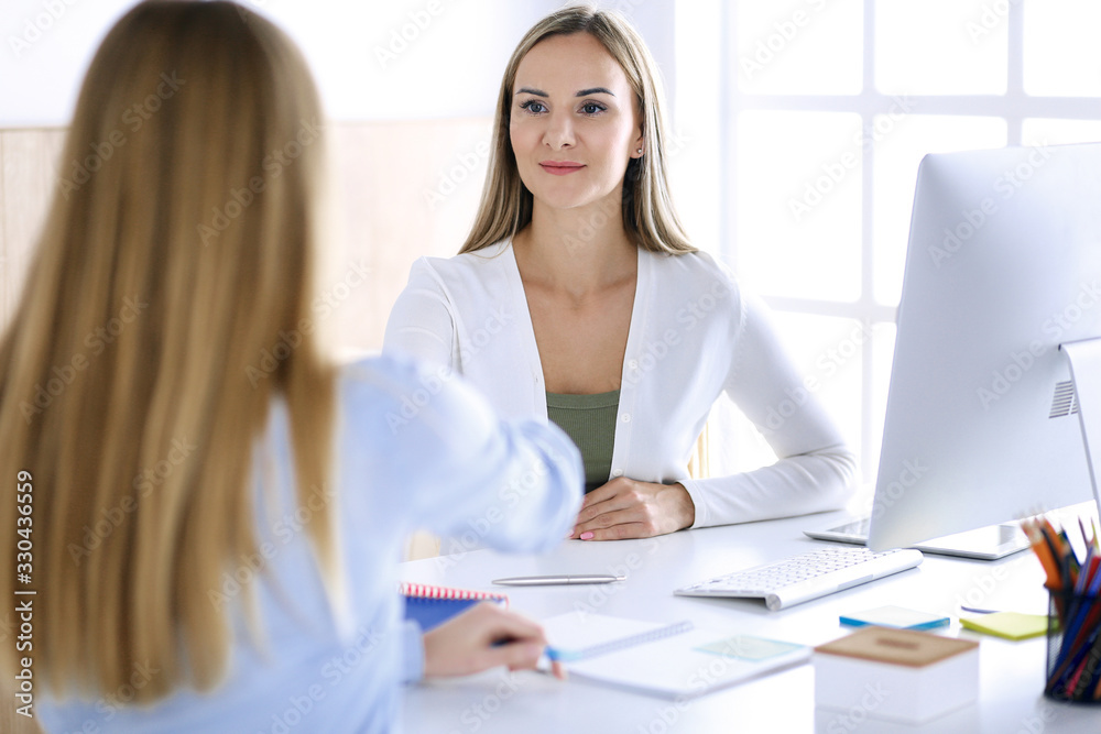 Business woman headshot while shaking hands with her female colleague or client in office. Casual white clothes style of business people. Audit, tax or lawyer concept Business woman headshot while shaking hands with her female colleague or client in office. Casual white clothes style of business people. Audit, tax or lawyer concept
