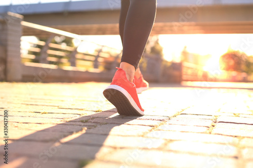 Close up of young woman in sports shoes jogging while exercising outdoors.