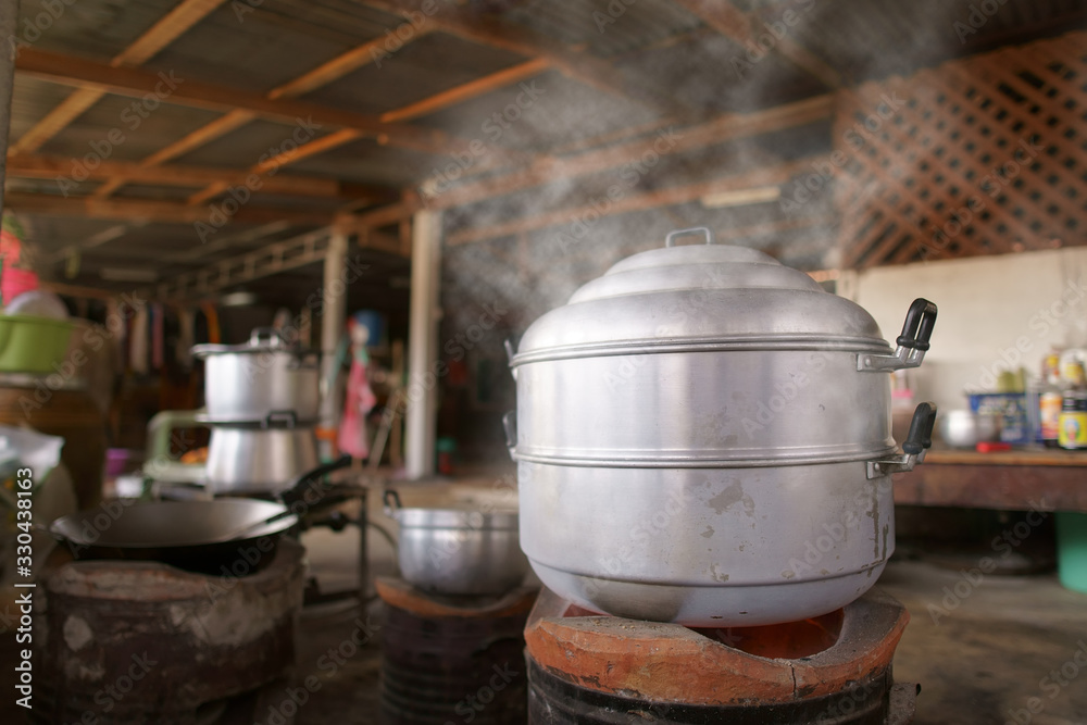hot steamer pot and boiling water on charcoal stove or brazier with white steam and smoke in traditional kitchen at countryside for food cooking or dessert to lunch at home and old or retro style hot steamer pot and boiling water on charcoal stove or brazier with white steam and smoke in traditional kitchen at countryside for food cooking or dessert to lunch at home and old or retro style