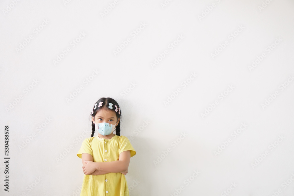 Asian child or kid girl wear N95 paper face mask for close mouth and sick on nose with cold cough and protect PM2.5 dust or influenza virus and bacteria from smoke and arms crossed on white background Asian child or kid girl wear N95 paper face mask for close mouth and sick on nose with cold cough and protect PM2.5 dust or influenza virus and bacteria from smoke and arms crossed on white background