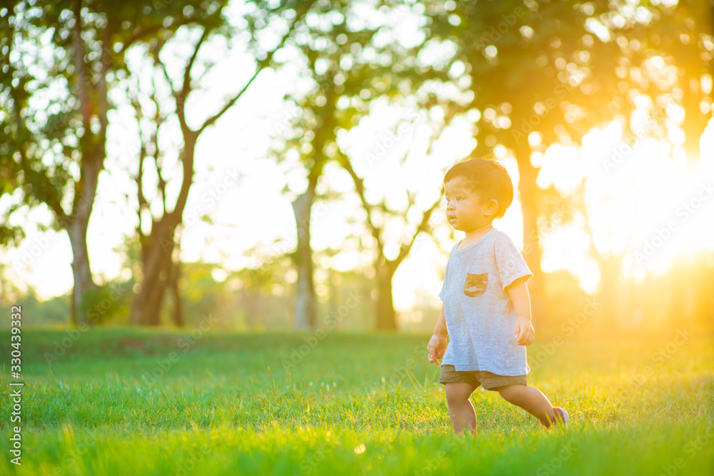 Adorable asian boy playing on green grass meadow sunset light Adorable asian boy playing on green grass meadow sunset light