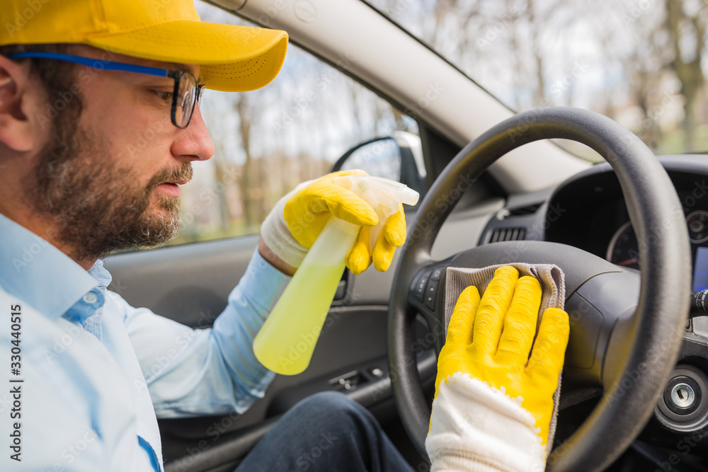 Car wash worker disinfecting vehicle interior. Stock Photo Adobe Stock