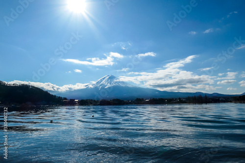 An idyllic view on Mt Fuji from the side of Kawaguchiko Lake, Japan. The mountain is surrounded by clouds. Serenity and calmness. The top of the volcano is covered with snow. Calm surface of the lake. © Chris