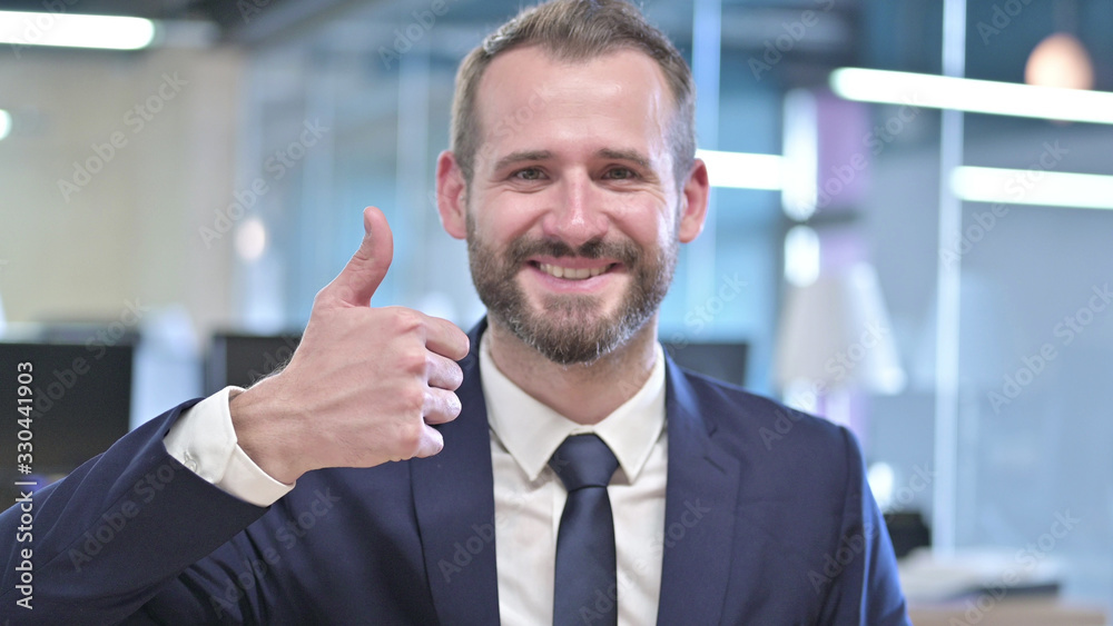 The Portrait of Cheerful Young Businessman showing Thumbs Up
