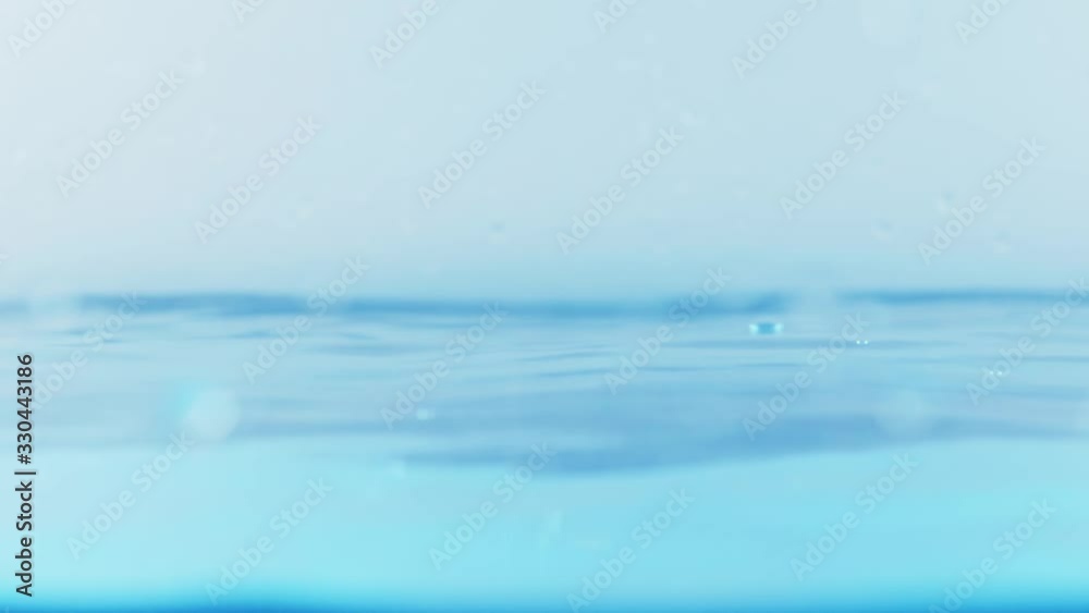 The clean water surface in slow motion fills the screen with water splashing shop the water drop and waving liquid surface with an air bubble. 1080p 29.97fps The clean water surface in slow motion fills the screen with water splashing shop the water drop and waving liquid surface with an air bubble. 1080p 29.97fps