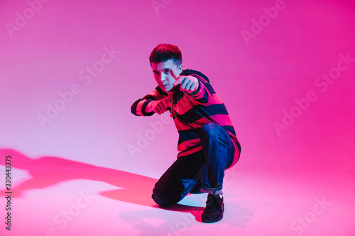Young Man in a Jumper Dancing Contemporary Dance in Studio. Breakdancing. Dance School Poster. Copy Space. Battle competition announcement. Pink and Blue Background.