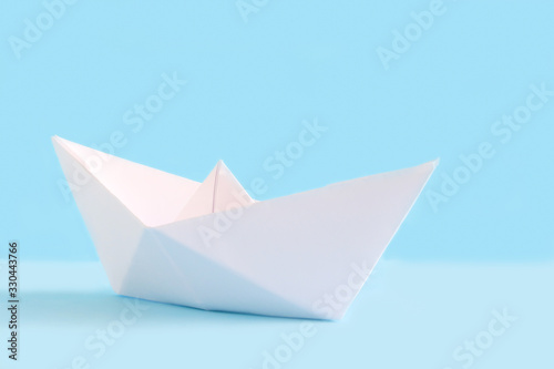 White paper handmade origami boat on the blue background. Cruise ship travel theme.