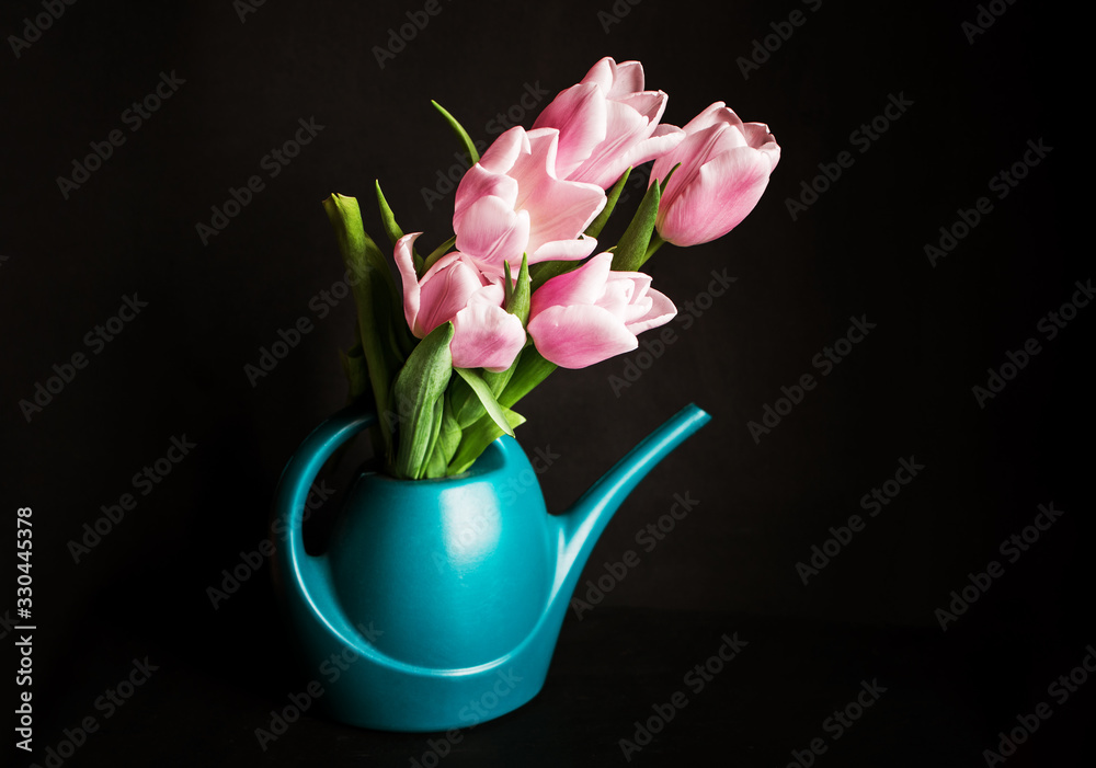 A beautiful bouquet of pink tulips in a water can on a dark background. A place for text.