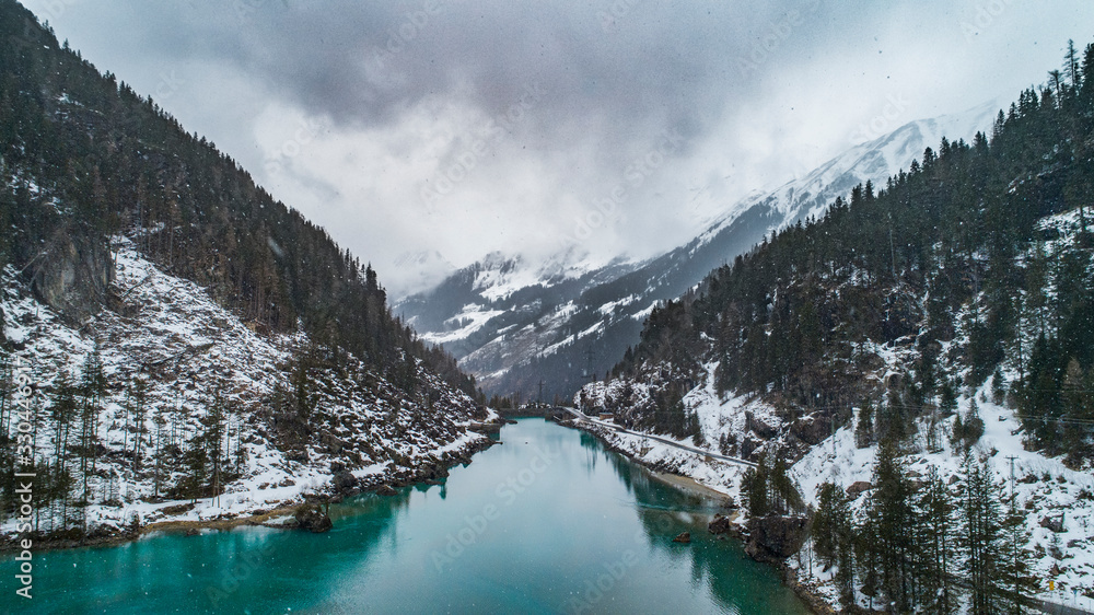 aerial shot of stausee mountain lake with blue cyan water lake with alps on background and road next to the lake