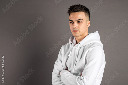 Young serious man posing in studio. Gray background