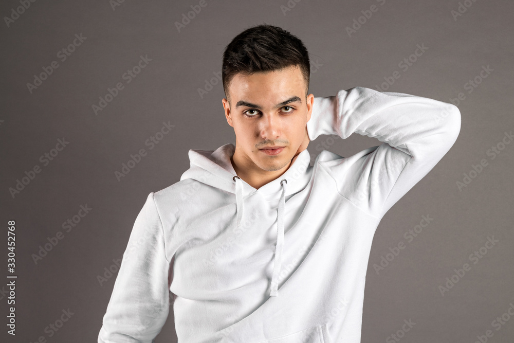 Obraz premium Young serious man posing in studio. Gray background