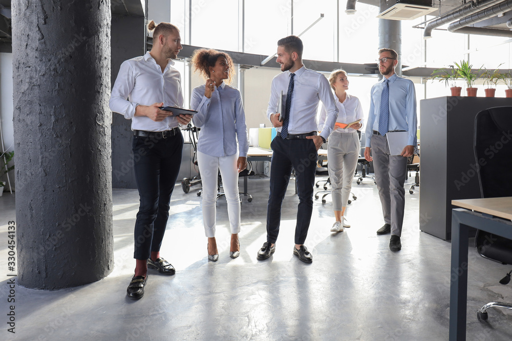 Obraz premium Modern business people discussing business and smiling while walking through the office corridor