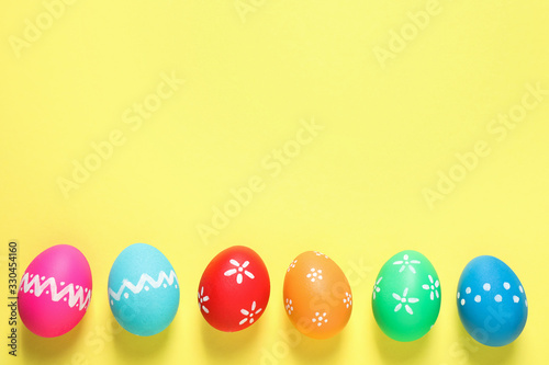 Colorful Easter eggs on yellow background, flat lay. Space for text