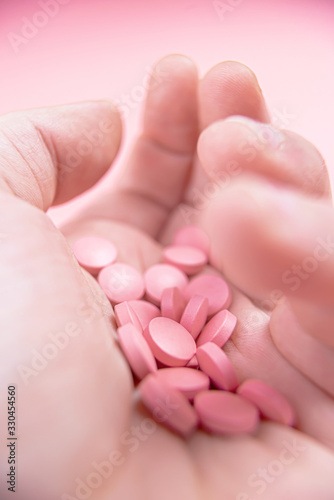 pink pills on a pink background in the palm of your hand