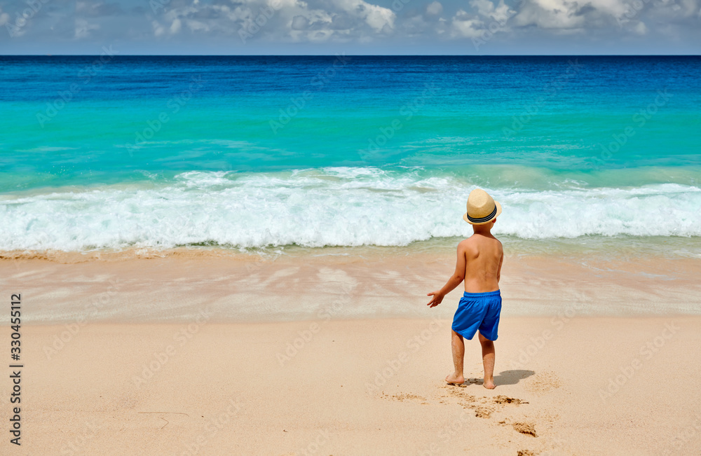 Three year old toddler boy walking on beach