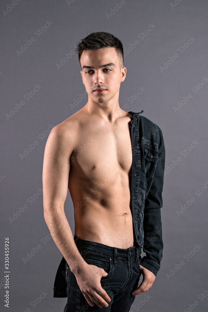 Sexy young man posing in studio. Gray background Sexy young man posing in studio. Gray background