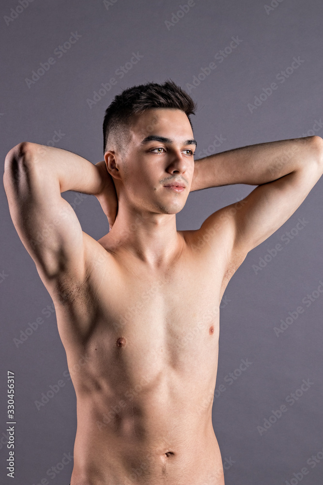 Fototapeta premium Sexy young man posing in studio. Gray background