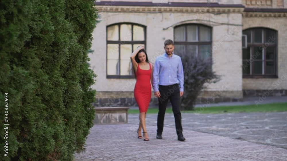 Beautiful couple Boyfriend and girlfriend walking and kissing on a park background. Man and woman love. Girl in a red dress and a guy. Beautiful couple Boyfriend and girlfriend walking and kissing on a park background. Man and woman love. Girl in a red dress and a guy.