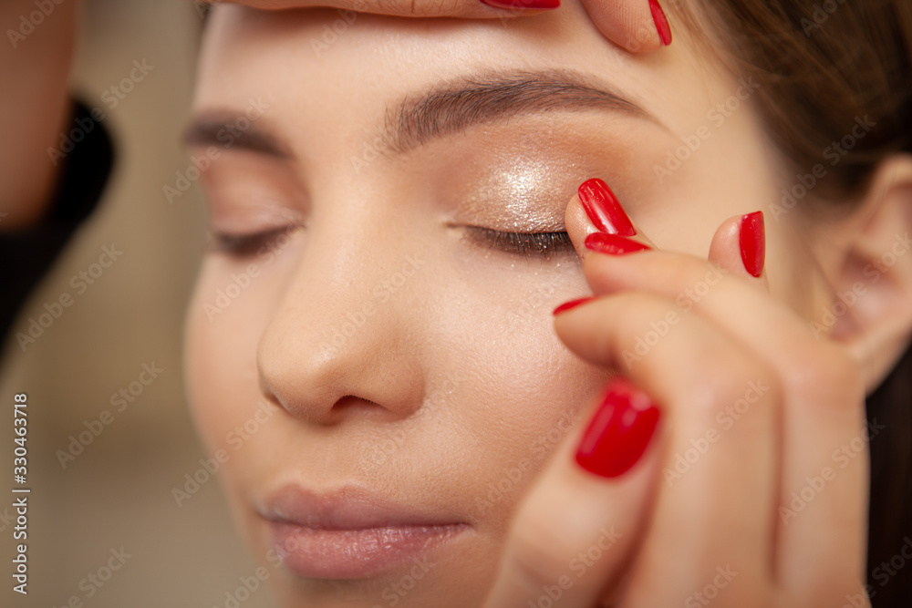 Close up cropped shot of a professional makeup artist applying primer on eyelids of a lovely young woman Close up cropped shot of a professional makeup artist applying primer on eyelids of a lovely young woman