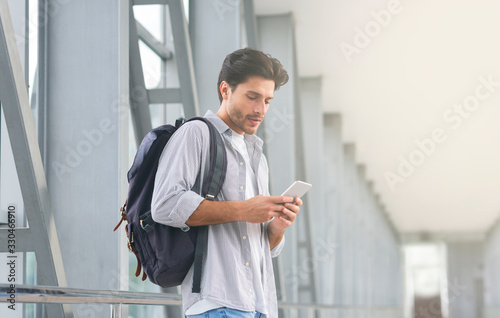 Online Check In. Man With Backpack Using Smartphone In Airport Terminal