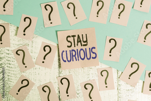 Text sign showing Stay Curious. Business photo showcasing attention through being inexplicable or highly unusual Scribbled and crumbling papers with thick cardboard above wooden table