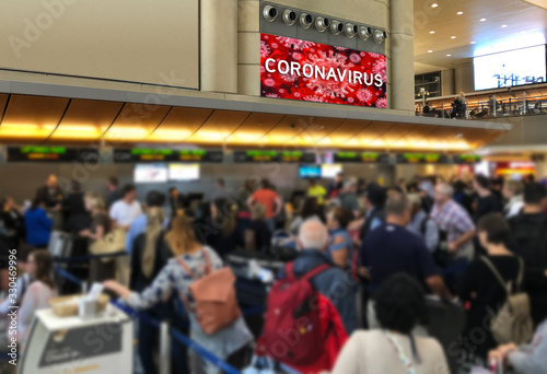 Crowd of people at airport check in desk with Corona Virus Sign