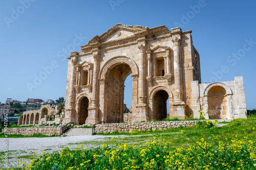 Arch of Hadrian at the roman ruins of Jerash, Jordan. Front view on a sunny day with blue sky. It features some unconventional, possibly Nabataean, architectural features, such as acanthus bases.