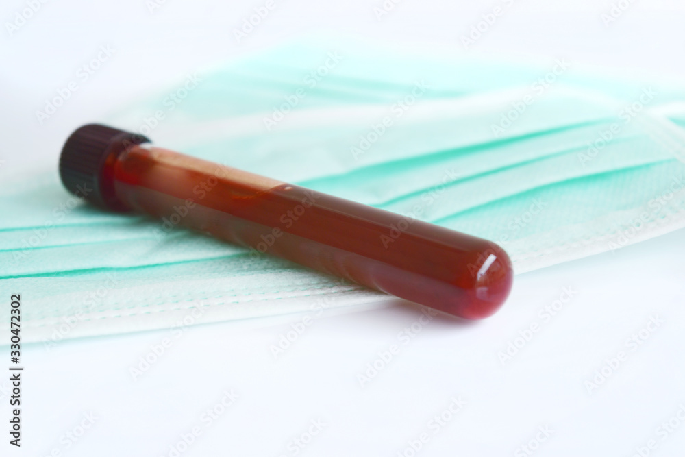Blood collection tubes for germ or corona virus detection on green mask and have a clean white background with copy space. Blood collection tubes for germ or corona virus detection on green mask and have a clean white background with copy space.