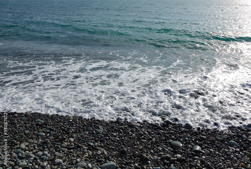 Sea shore with pebbles. wet sea pebbles on the beach and quiet sea surf Sea shore with pebbles. wet sea pebbles on the beach and quiet sea surf