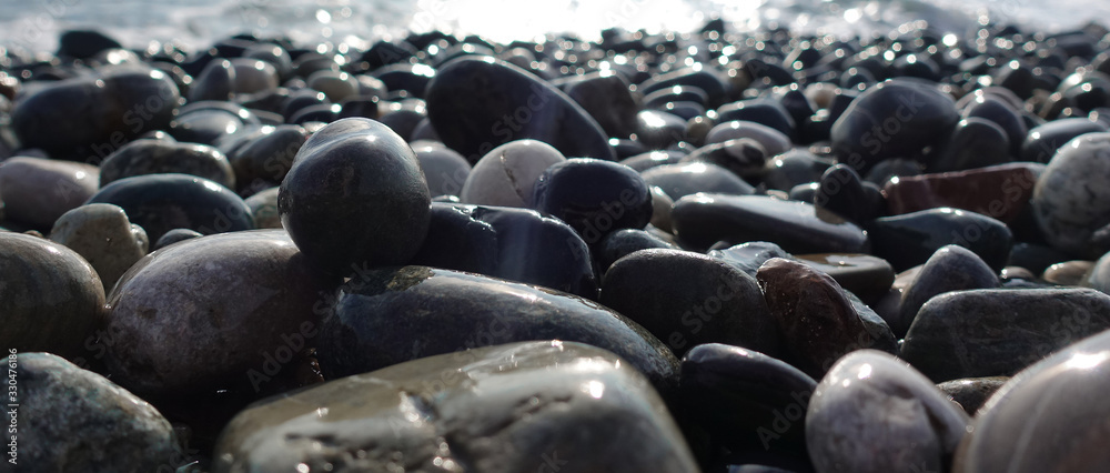 Fototapeta premium Sea shore with pebbles. wet sea pebbles on the beach and quiet sea surf