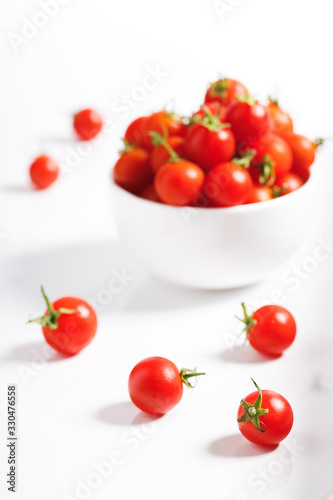 red cherry tomato in ceramic bowl on white background