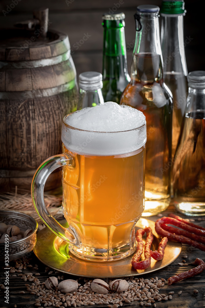 Light frothing beer in a glass, on an old background. Light frothing beer in a glass, on an old background.