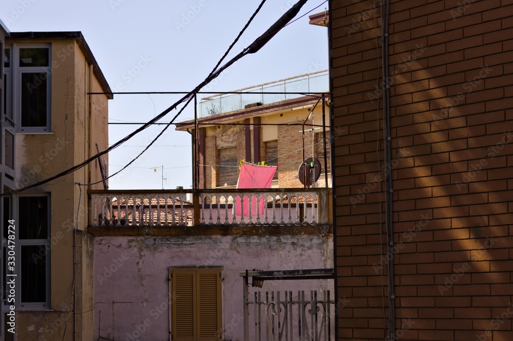 A pink bath towel hanging on a wire with clothespins on the balcony of a rural house (Pesaro, Italy, Europe)