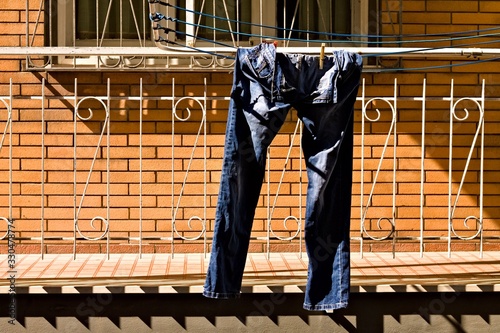 A pair of blue jeans hanging on the clotheshorse with clothespins out of the balcony (Pesaro, Italy, Europe)