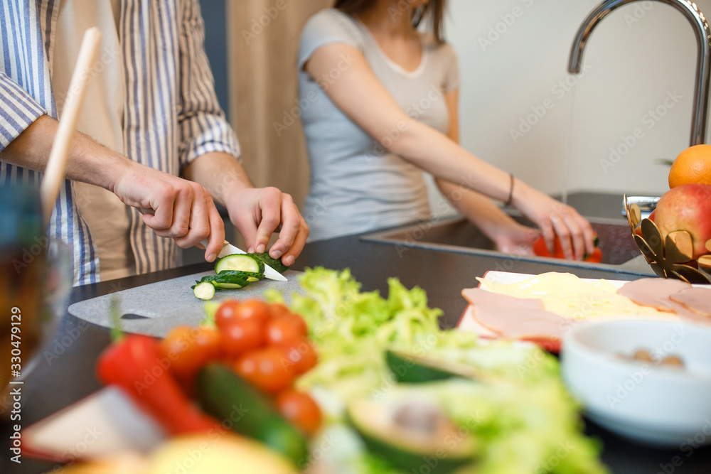 Close up photo, man cutting cucumber on cutting board, woman waching pepper, cooking time concept