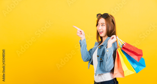 woman teen smiling standing with sunglasses excited holding shopping bags multi color pointing to side