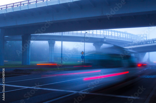 Cars race along the highway. Expressway in the fog. Transport infrastructure. Traffic management at different levels. Traffic on the Expressway on a foggy evening.