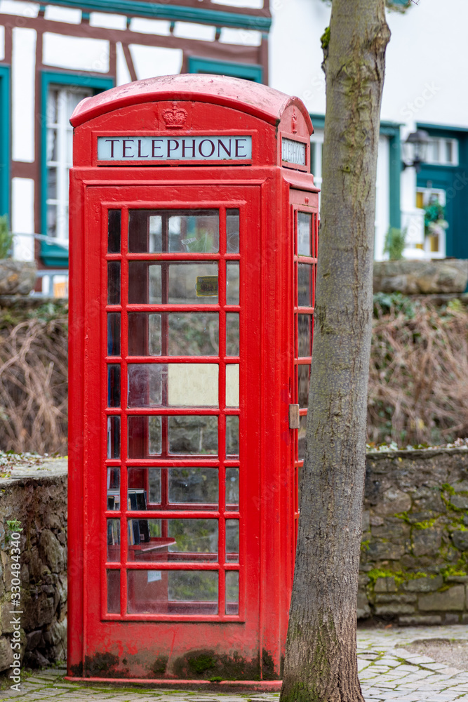 Red english telephone booth in front of a stone wall in Bad Muenstereifel Red english telephone booth in front of a stone wall in Bad Muenstereifel