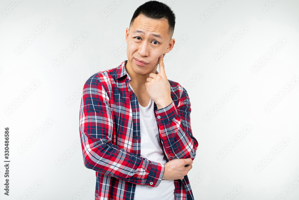 cool asian guy in a plaid shirt wide open isolated on a white studio background with copy space cool asian guy in a plaid shirt wide open isolated on a white studio background with copy space
