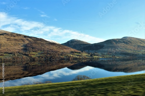tres montañas bajo un cielo azul que se ven reflejadas en un lago