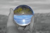 Reflection of desert landscape in glass ball, only the orb is in color the rest is black and white. 