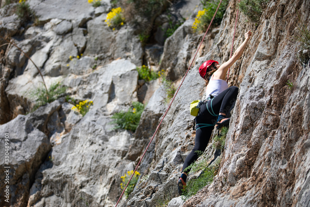 Female climber is climbing the rock.