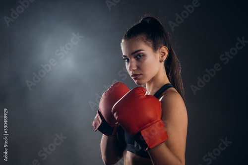 Image of a beautiful young amazing sports fitness caucasian woman boxer posing isolated over gray background in red gloves.