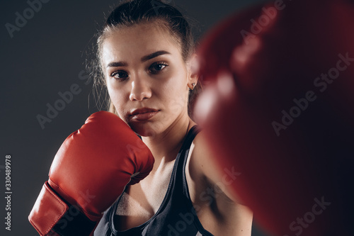 Image of a beautiful young amazing sports fitness caucasian woman boxer posing isolated over gray background in red gloves. © Owl-vision-studio