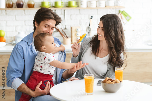 Millennial parents playing with baby boy at kitchen