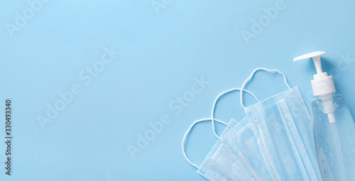 Sanitizer gel or antibacterial soap and face mask for coronavirus preventive measure, top view photo